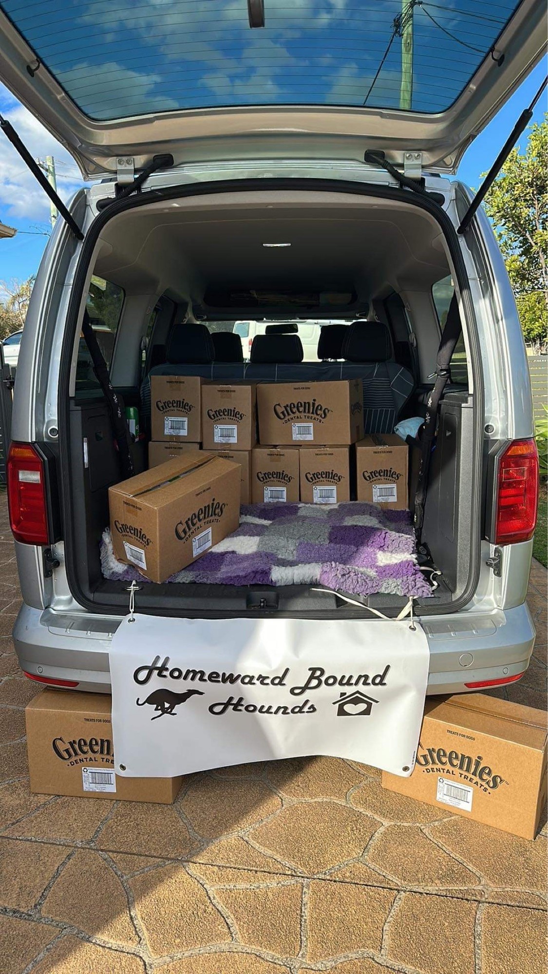 Silver van with boxes of Greenies in the back and a white and black sign for Homeward Bound Hounds